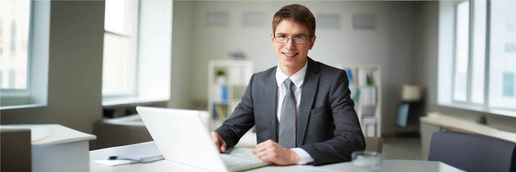 Contador jovem e sorridente em escritório, verificando seus honorários contábeis no notebook